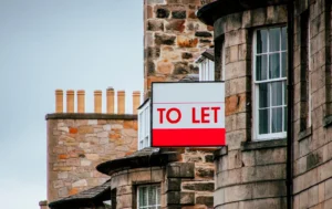 A-TO-LET-sign-hanging-on-the-side-of-a-building-with-a-cloudy-sky
