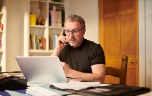 A-man-talking-on-the-phone-with-documents-related-to-Landlord-Guaranteed-Rent