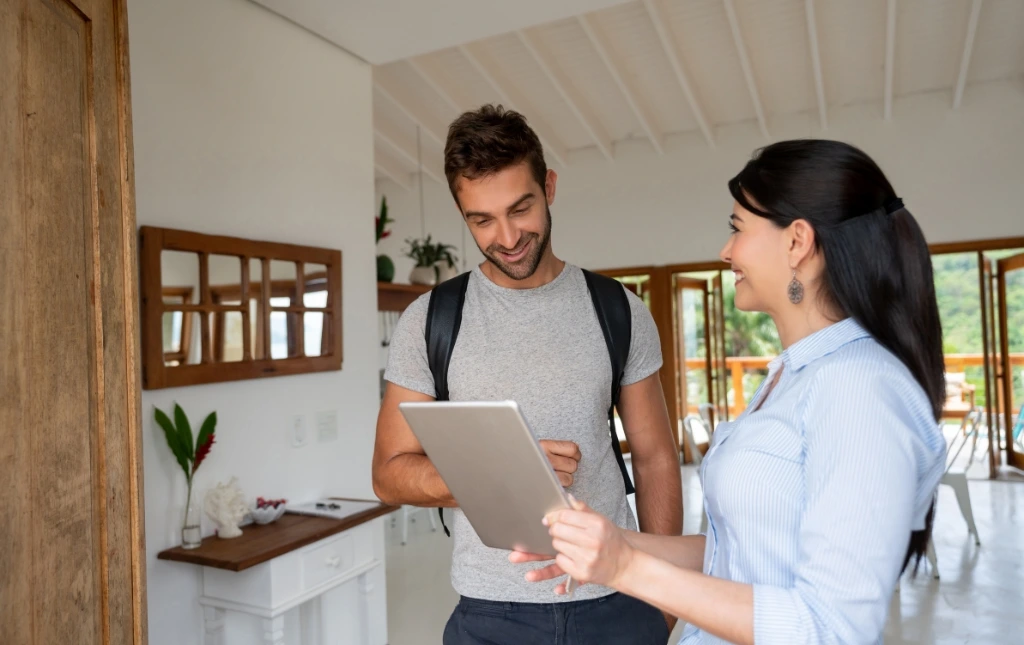 A-man-and-a-woman-discussing-shared-housing-in-a-modern-living-room-with-the-woman-holding-a-tablet-and-smiling