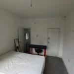 A-bedroom-with-a-bed-desk-chair-mirror-and-door-leading-to-an-en-suite-bathroom
