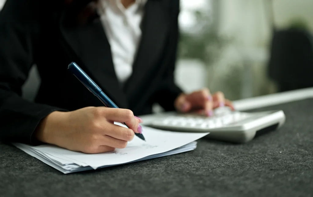 C2-Conversions-Woman-writing-with-calculator-on-desk